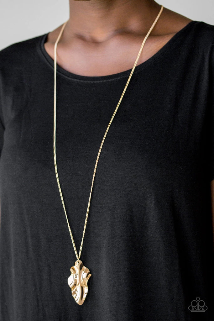 An elongated gold chain gives way to a rippling gold leaf-like pendant for a seasonal look. Features an adjustable clasp closure.  Sold as one individual necklace. Includes one pair of matching earrings.