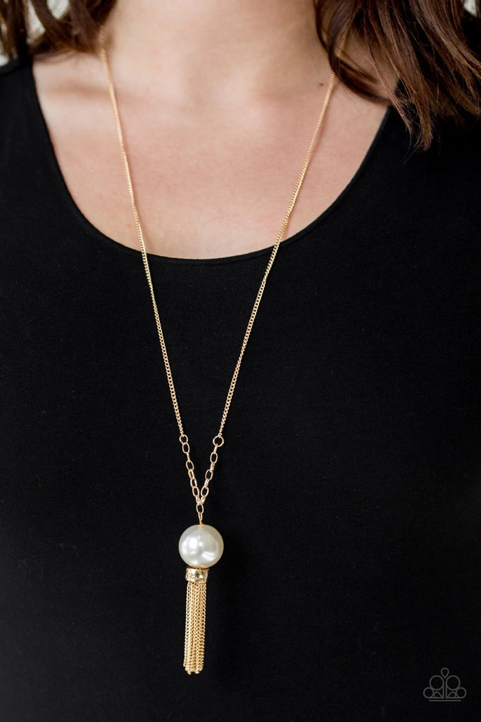 A dramatic pearly white bead swings from the bottom of an elegantly elongated gold chain. Featuring a hammered fitting, a gold tassel streams from the bottom of the colorful pendant for a refined finish. Features an adjustable clasp closure.  Sold as one individual necklace. Includes one pair of matching earrings.