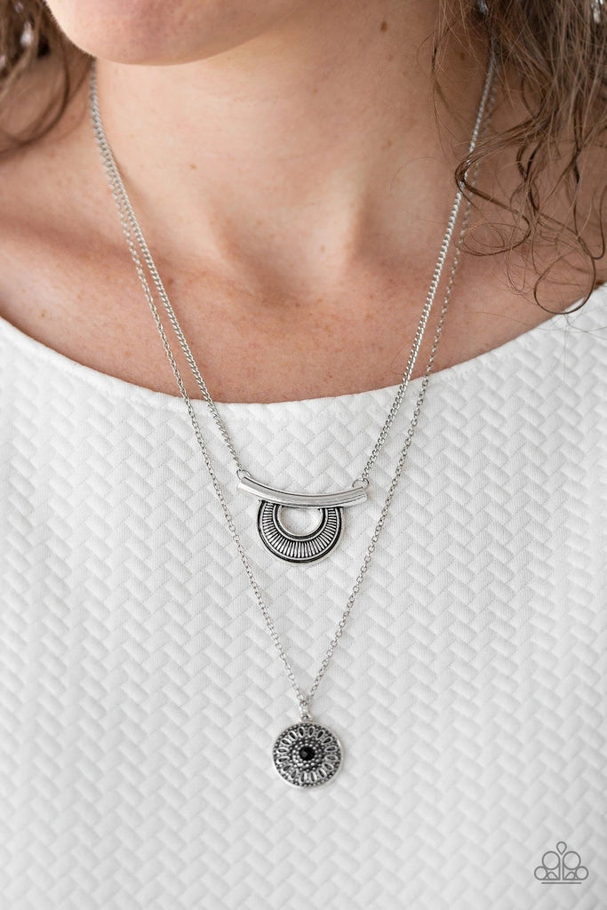 Radiating with linear patterns, a shimmery silver frame swings from the uppermost chain above a silver disc radiating with floral detail. A dainty black bead dots the center of the lowermost pendant for a colorful finish. Features an adjustable clasp closure.  Sold as one individual necklace. Includes one pair of matching earrings.  