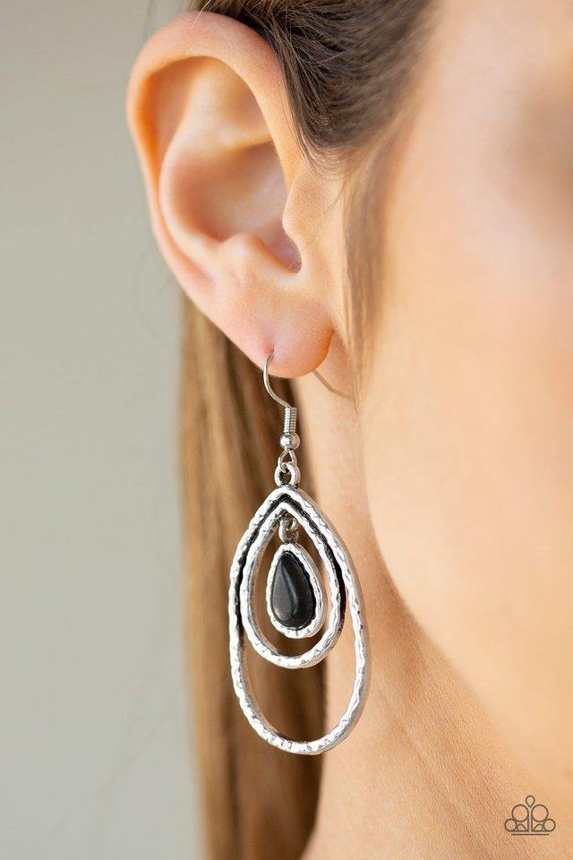 Nestled inside of a hammered silver frame, a dainty black stone teardrop swings from the top of a doubled silver teardrop frame for an abstract look. Earring attaches to a standard fishhook fitting.  Sold as one pair of earrings.