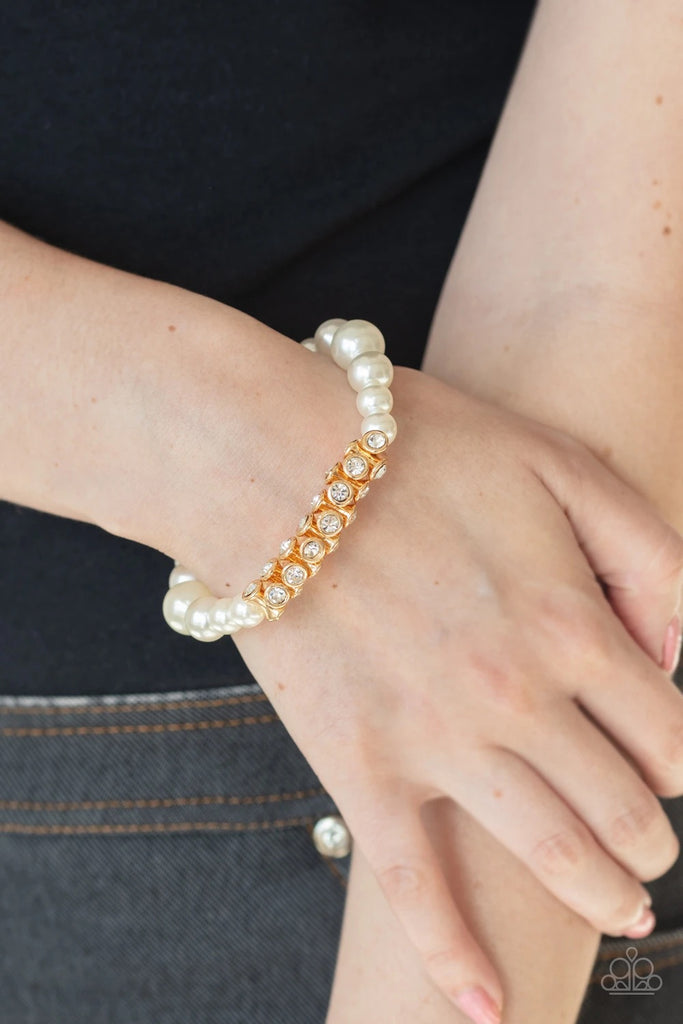 A collection of white pearls and white rhinestone dotted gold frames are threaded along stretchy bands around the wrist, creating a sparkling centerpiece.  Sold as one individual bracelet.