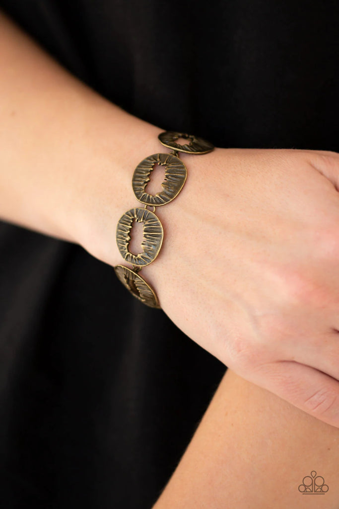 Featuring asymmetrical cutout centers, textured brass discs connect across the wrist for an abstract look. Features an adjustable clasp closure.  Sold as one individual bracelet.