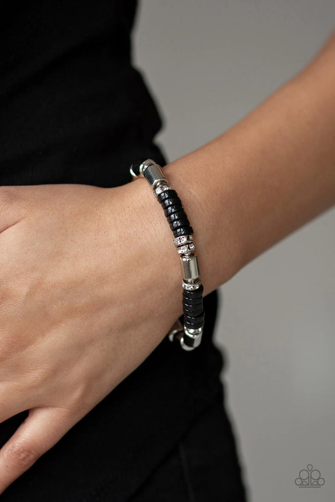 A collection of white rhinestone encrusted rings, silver accents, and shiny black beads are threaded along a stretchy band around the wrist for a whimsical flair.  Sold as one individual bracelet.