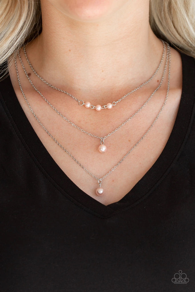 A trio of pearly pink beads give way to layers of solitaire pink pearl pendants below the collar for a refined flair. Features an adjustable clasp closure.  Sold as one individual necklace. Includes one pair of matching earrings.