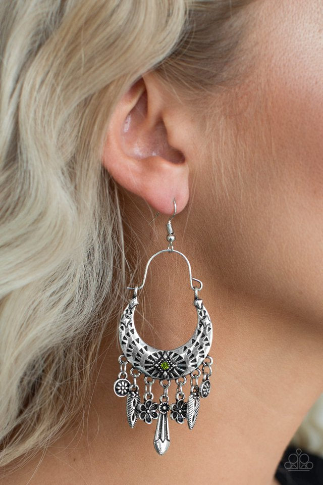 Stamped in triangular textures, a shimmery silver crescent frame gives way to a fringe featuring glistening floral and abstract charms. Suspended by a dainty wire fitting, the tribal inspired frame is dotted with a dainty green rhinestone for a colorful finish. Earring attaches to a standard fishhook fitting.   Sold as one pair of earrings.  