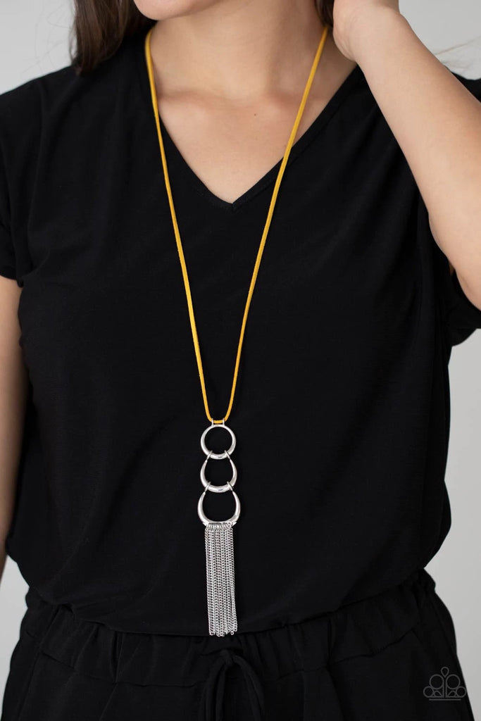 A bold silver ring gives way to two interlocking half moon silver frames at the bottom of a lengthened piece of yellow suede. Shimmery silver chains swing from the bottom of the display, adding flirty movement to the stationary pendant. Features an adjustable clasp closure.  Sold as one individual necklace. Includes one pair of matching earrings.