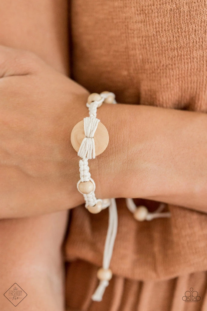 Infused with a wooden button-like centerpiece, pieces of earthy white cording delicately knot wooden beads in place around the wrist for a homespun braided look. Features an adjustable sliding knot closure.  Sold as one individual bracelet.