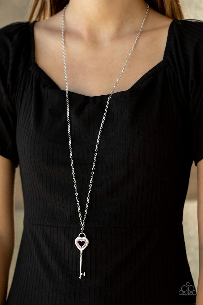 Encrusted in dainty pink rhinestones, a heart-shaped silver key pendant swings from the bottom of a lengthened silver chain for a flirty look. Features an adjustable clasp closure.  Sold as one individual necklace. Includes one pair of matching earrings.