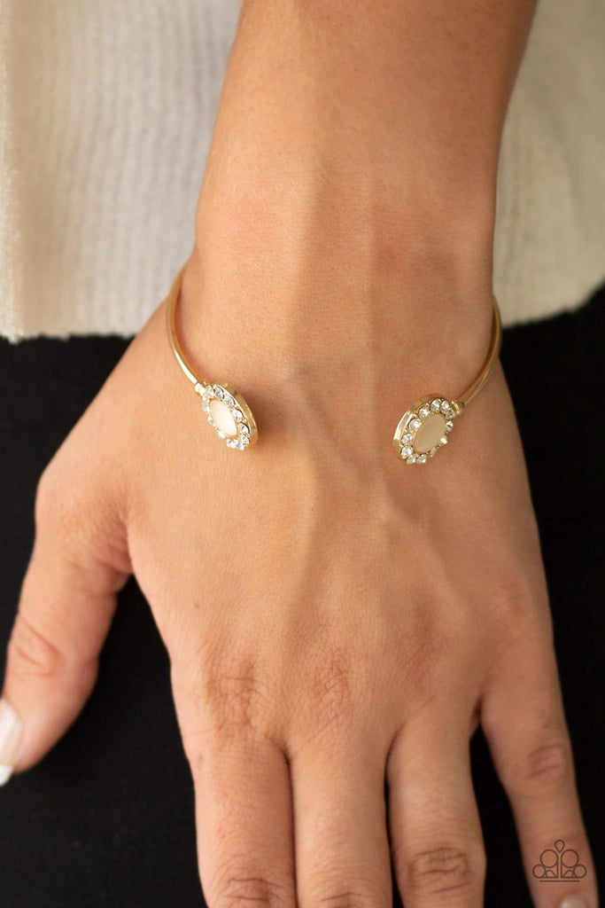 Featuring glowing cat's eye stones, glittery white rhinestone encrusted fittings dot the ends of a dainty gold cuff for a refined flair.  Sold as one individual bracelet.