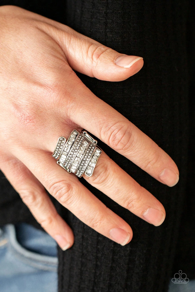 Dotted with pairs of dainty white rhinestones and glassy emerald cut rhinestones, stacks of silver bands wrap across the front of the finger for a jaw-dropping dazzle. Features a stretchy band for a flexible fit.  Sold as one individual ring.