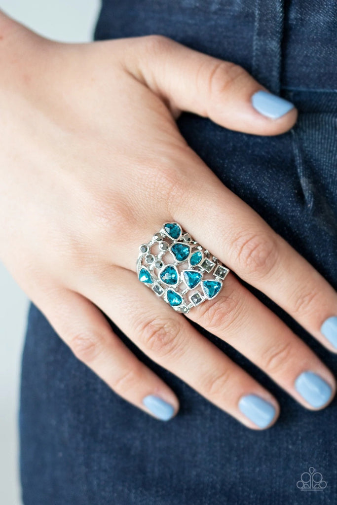 A glittery blue collection of oval, triangular, and heart shaped rhinestones scatter across rows of dainty layered silver bars. Dainty hematite rhinestones and smoky square rhinestones sporadically dot the finger, adding edgy drama to the flirtatious centerpiece. Features a stretchy band for a flexible fit.  Sold as one individual ring.