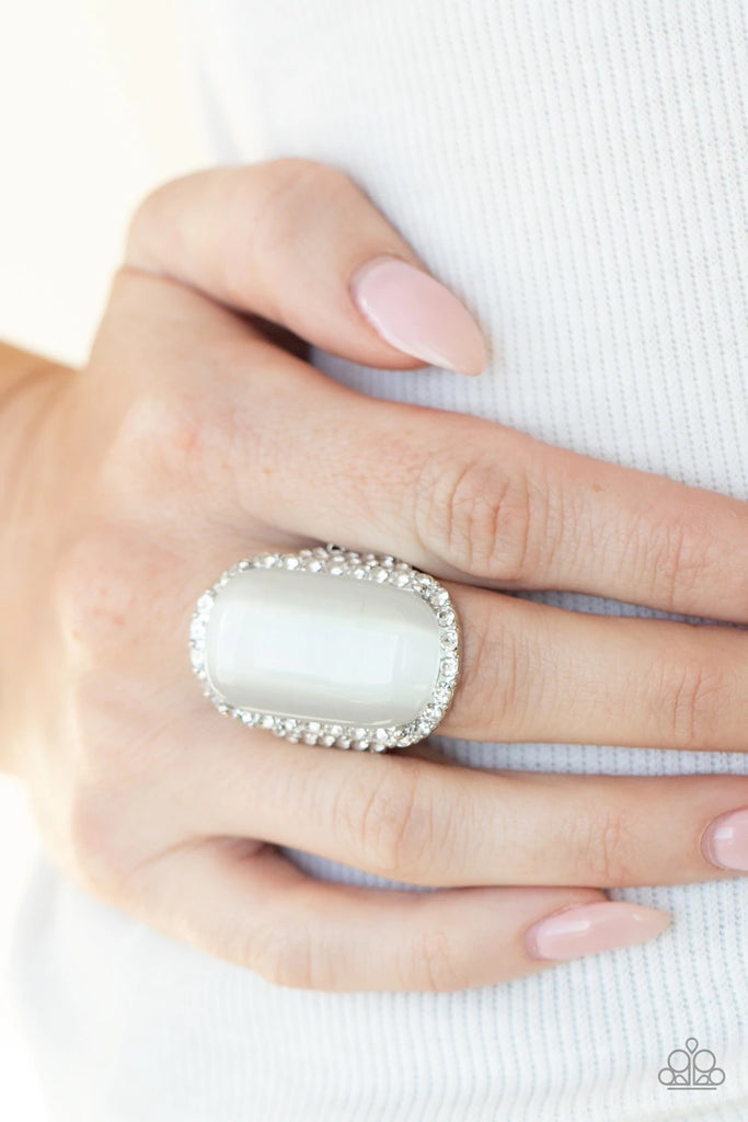 An oversized white cat's eye stone sits atop an icy silver frame bedazzled in blinding white rhinestones for a luxurious look. Features a stretchy band for a flexible fit.  Sold as one individual ring.