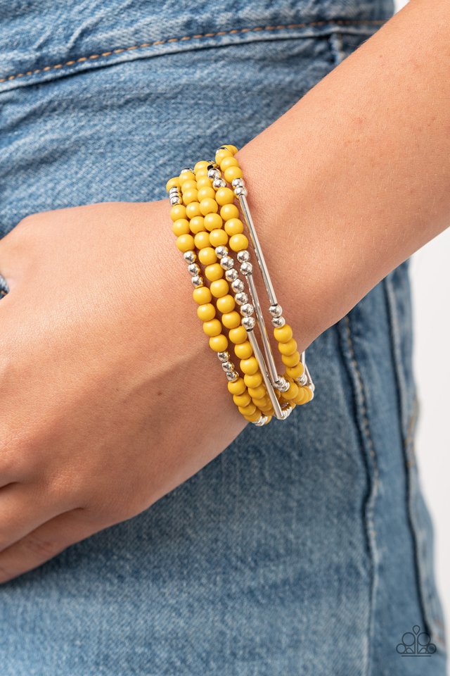 An array of shimmery silver beads, silver rods, and hearty yellow beads are threaded along stretchy bands around the wrist, creating colorful layers.  Sold as one set of five bracelets.