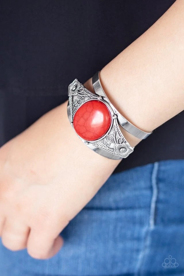 A round red stone is pressed into the center of a silver frame etched and embossed in whimsical floral detail, creating a seasonal centerpiece atop a thick silver cuff. Sold as one individual bracelet.