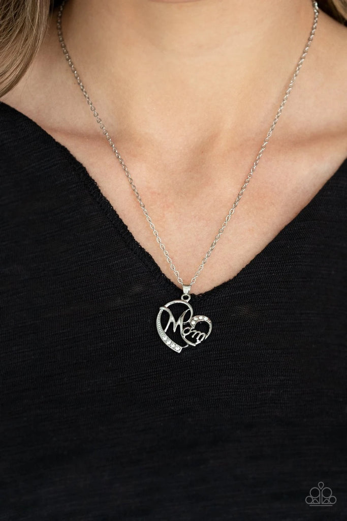 Encrusted in sections of dainty white rhinestones, a shimmery silver heart frame swirls into the word, "Mom", across the center. The charming pendant swings from the bottom of a dainty silver chain below the collar for a timeless finish. Features an adjustable clasp closure.  Sold as one individual necklace. Includes one pair of matching earrings.
