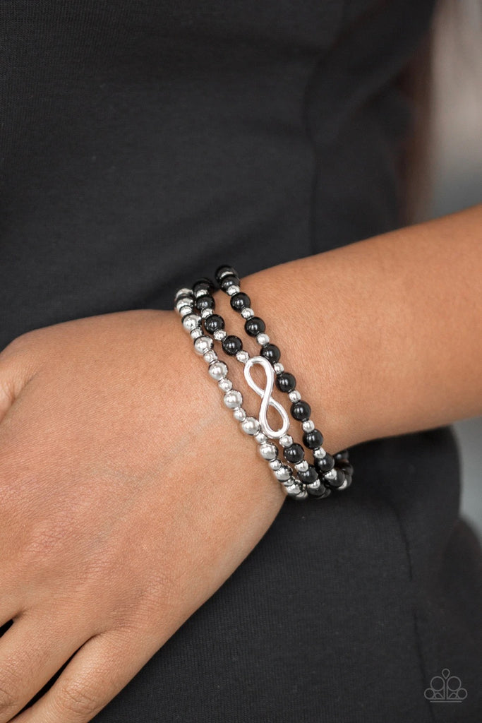 Polished black and shiny silver beads are threaded along stretchy bands, creating colorful layers around the wrist. A dainty silver infinity charm adorns one strand for a whimsical finish.  Sold as one set of three bracelets.  