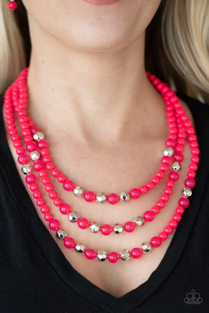 A colorful collection of polished pink beads, faceted silver beads, and opaque pink beads are threaded along invisible wires across the chest, creating vivacious layers. Features an adjustable clasp closure.  Sold as one individual necklace. Includes one pair of matching earrings.