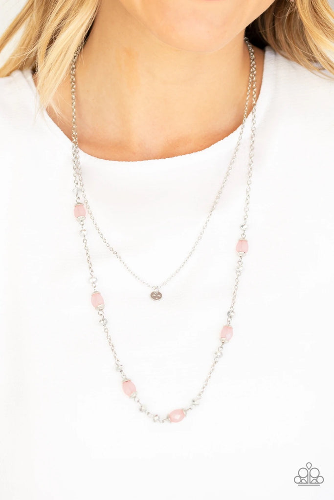 A dainty hammered disc is suspended above a glistening silver chain sparkling with dainty silver accents, metallic crystal-like beads, and opaque pink beads for a whimsical look. Features an adjustable clasp closure.  Sold as one individual necklace. Includes one pair of matching earrings.