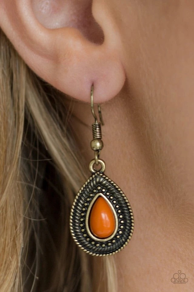 A hearty orange bead is pressed into a studded brass teardrop, creating a rustic lure. Earring attaches to a standard fishhook fitting.  Sold as one pair of earrings.