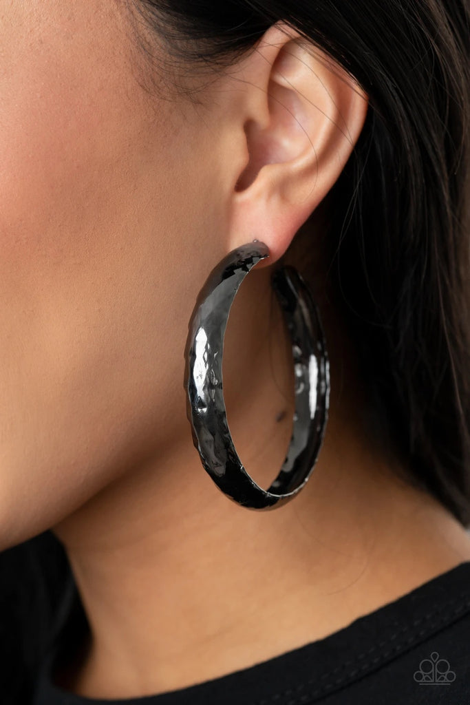A thick piece of gunmetal has been heavily hammered and delicately curved into a dramatically handcrafted hoop. Earring attaches to a standard post fitting. Hoop measures approximately 2 ½” in diameter.  Sold as one pair of hoop earrings.
