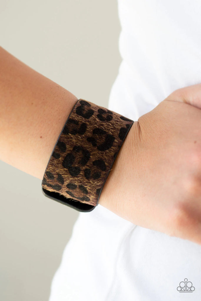 A fuzzy brown cheetah pattern is printed across the front of thick black leather band for a wild look. Features an adjustable snap closure.  Sold as one individual bracelet.