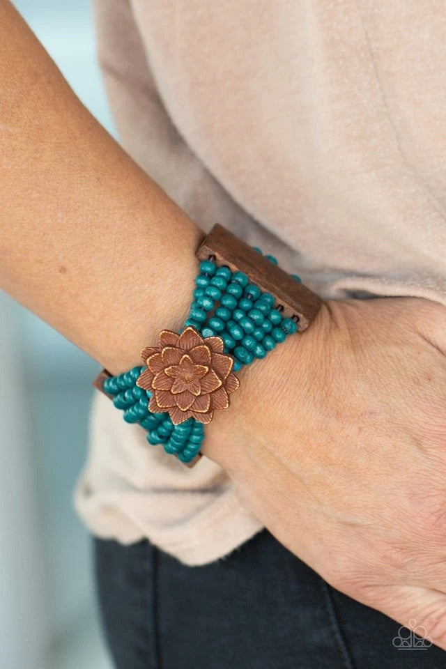 Held together by oversized rectangular fittings and wooden floral frames, strands of refreshing blue wooden beads are threaded along stretchy bands that weave around the wrist for a colorful island inspired look.  Sold as one individual bracelet.