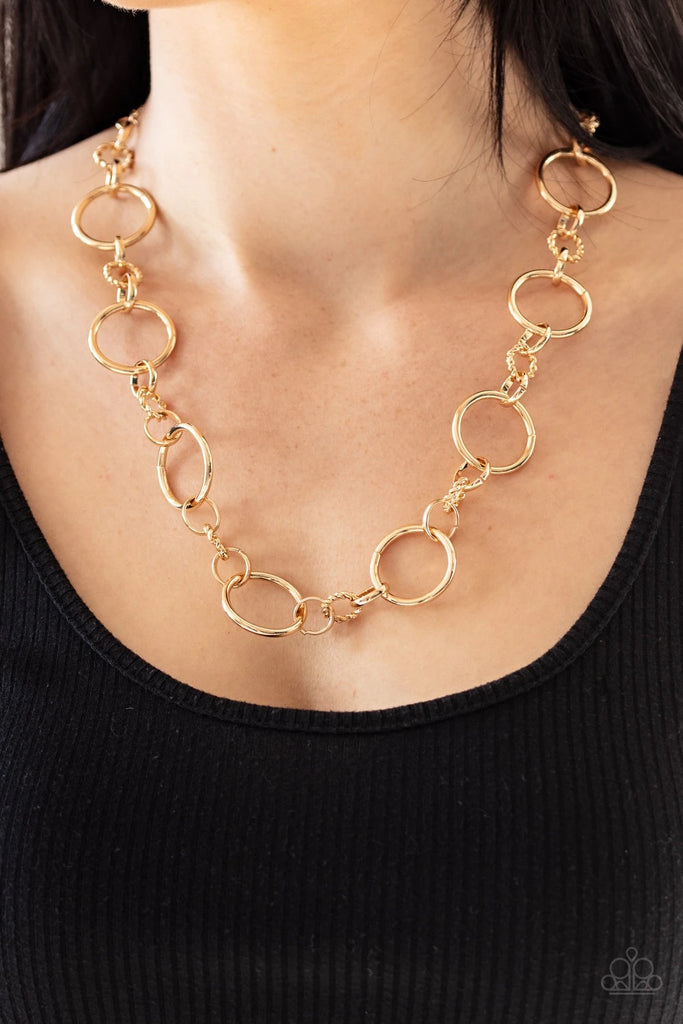 Over sized gold hoops link with dainty twisted gold rings below the collar for a classic combination. Features an adjustable clasp closure.  Sold as one individual necklace. Includes one pair of matching earrings.