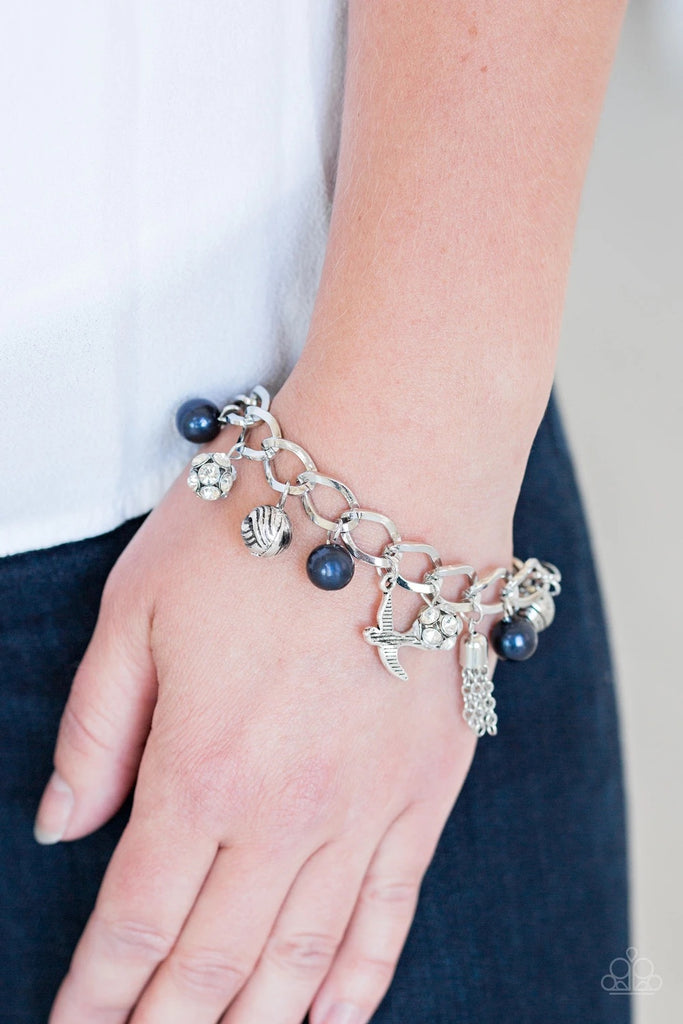 Blue pearls, ornate silver beads, and white rhinestone encrusted accents swing from a dramatic silver chain. A shimmery silver bird charm and silver tassel are added to the display, creating a whimsical fringe around the wrist. Features an adjustable clasp closure.  Sold as one individual bracelet.