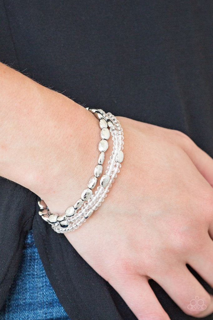 Infused with hints of silver, dainty white crystal-like beads are threaded along stretchy bands, creating whimsical layers across the wrist.  Sold as one set of three bracelets.  