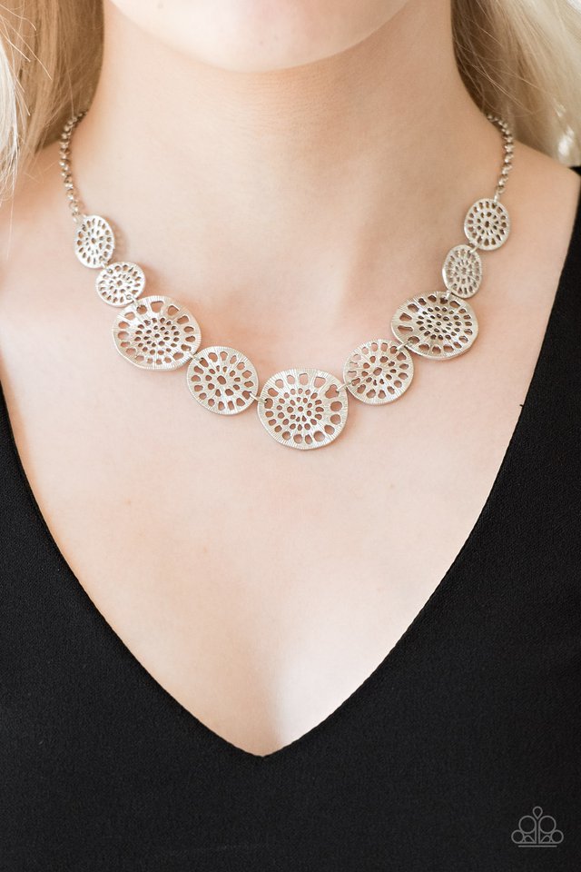 Featuring airy stenciled patterns, shimmery silver discs link below the collar for a whimsical asymmetrical look. Features an adjustable clasp closure.  Sold as one individual necklace. Includes one pair of matching earrings.  