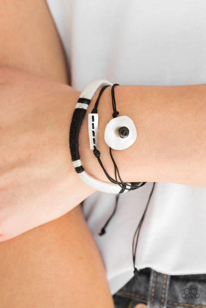 Featuring wooden and hammered metallic accents, strands of black cording join a black and white threaded band around the wrist for a seasonal look. Features an adjustable sliding knot closure.  Sold as one individual bracelet.