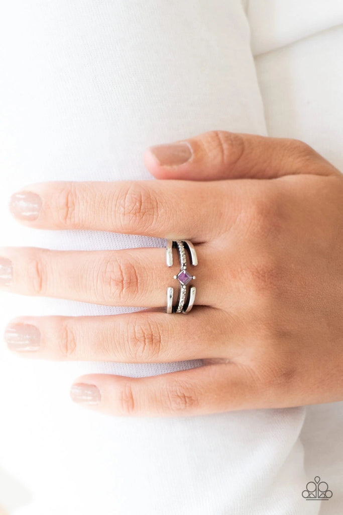 Glistening silver bars gather around a sparkling hematite rhinestone encrusted band. Featuring a regal square cut, a purple rhinestone is pressed into the center for an edgy finish. Features a dainty stretchy band for a flexible fit.  Sold as one individual ring.