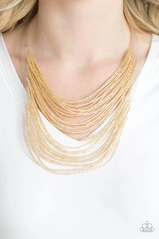 Strand after strand of metallic gold seed beads fall together to create a bold statement piece. Features an adjustable clasp closure.  Sold as one individual necklace. Includes one pair of matching earrings.