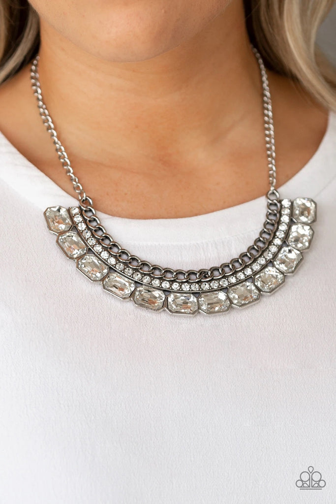 Stationary rows of shimmery silver chain, glittery white rhinestones, and glassy white emerald-cut gems coalesce into a bold pendant below the collar. Features an adjustable clasp closure.  Sold as one individual necklace. Includes one pair of matching earrings.  