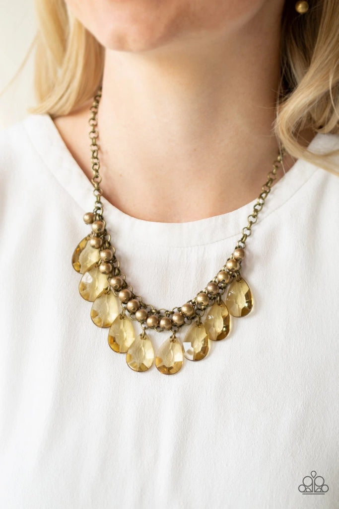 A row of antiqued brass beads gives way to glassy brass teardrops, creating a bold tone on tone fringe below the collar. Features an adjustable clasp closure.  Sold as one individual necklace. Includes one pair of matching earrings.