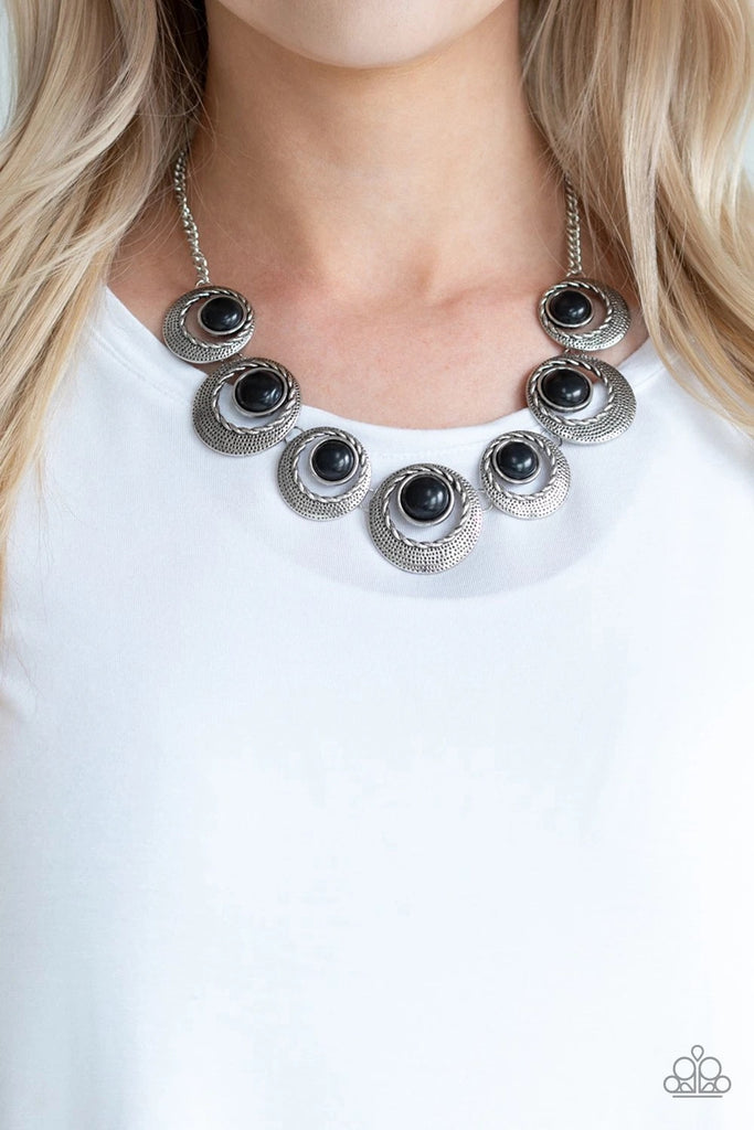 Featuring black stone accents, hammered and textured circular frames link below the collar for an artisan inspired look. Features an adjustable clasp closure.  Sold as one individual necklace. Includes one pair of matching earrings.