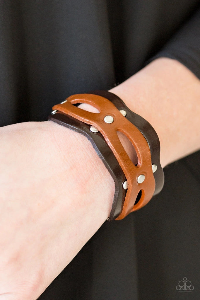 Brushed in a shiny finish, an airy strip of light brown leather is studded across the front of a scalloped brown leather band for a rugged look. Features an adjustable snap closure.  Sold as one individual bracelet.  
