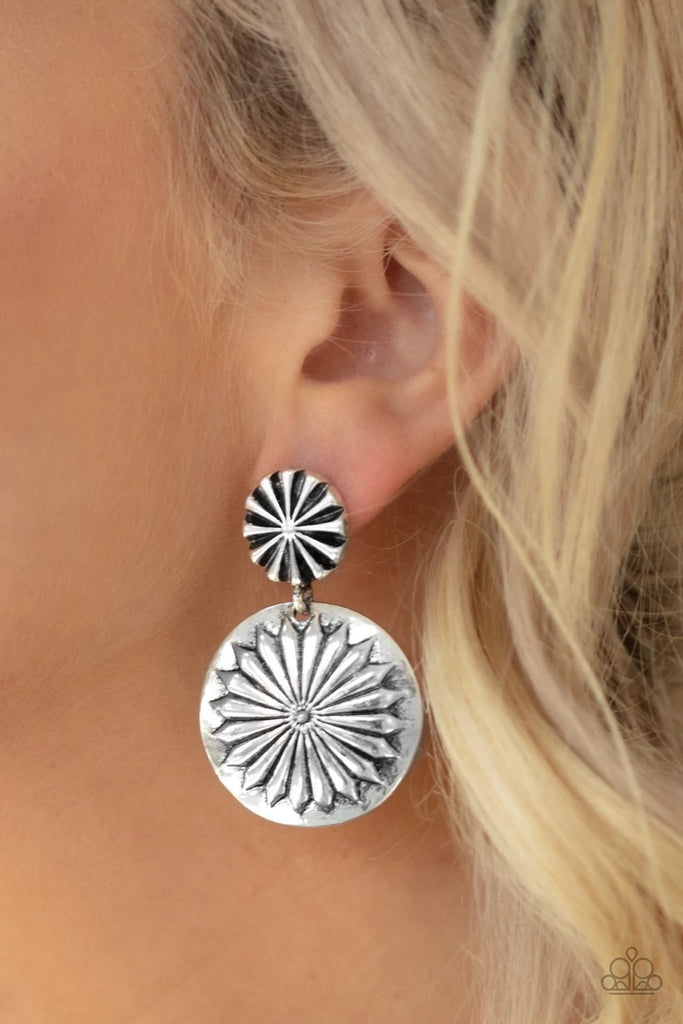 Stamped in a floral pattern, a dainty silver disc attaches to a larger silver disc embossed in a shimmery silver flower, creating a whimsical lure. Earring attaches to a standard post fitting.  Sold as one pair of post earrings.