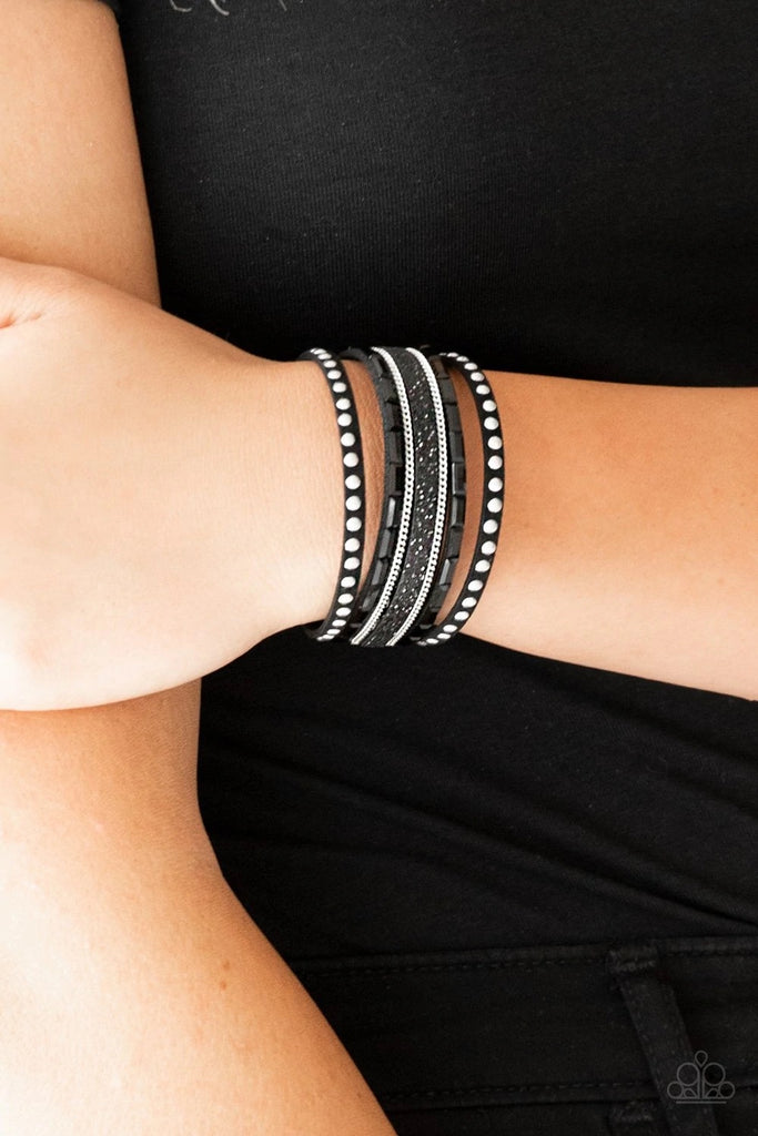 Shimmery silver studs, dainty silver chains, and black emerald style cut rhinestones are encrusted along a black suede band dusted in a sparkling center for a sassy look. Features an adjustable snap closure.  Sold as one individual bracelet.