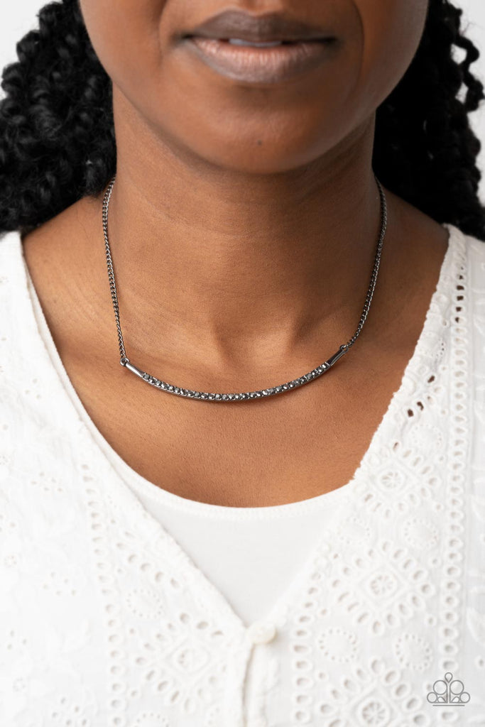 Encrusted in smoky hematite rhinestones, a curved gunmetal bar bows below the collar for a smoldering style. Features an adjustable clasp closure.  Sold as one individual necklace. Includes one pair of matching earrings.  