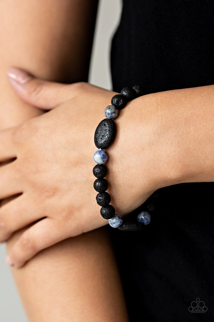 A collection of black lava rocks and earthy blue stone beads are threaded along a stretchy band around the wrist for a seasonal look.  Sold as one individual bracelet.  