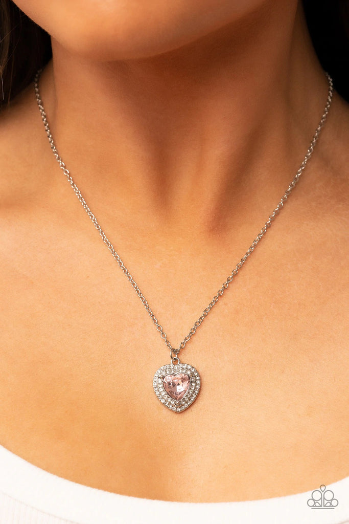 Bordered in stack rows of glassy white rhinestones, a twinkly pink heart shaped gem sparkles at the center of a dainty silver chain for a flirtatious fashion. Features an adjustable clasp closure.  Sold as one individual necklace. Includes one pair of matching earrings.