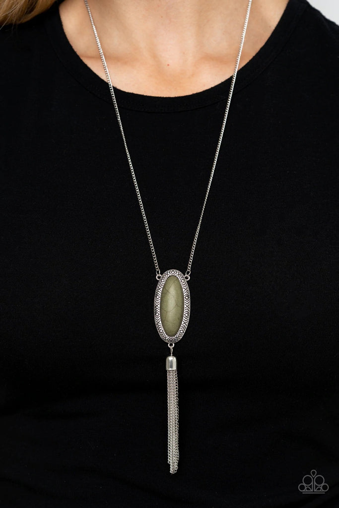 An oval Military Olive stone is pressed into a glistening silver frame stamped in antiqued tribal inspired patterns. A shimmery silver chain tassel swings from the bottom of the earthy pendant for a whimsical finish. Features an adjustable clasp closure.  Sold as one individual necklace. Includes one pair of matching earrings.