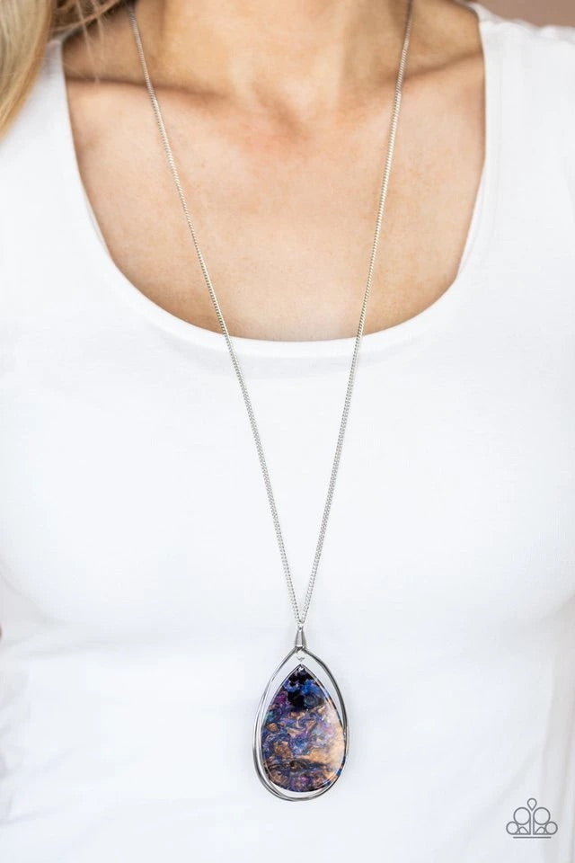 Swirling with an iridescent watercolor background, an acrylic teardrop swings from the bottom of a silver teardrop frame, creating a dreamy pendant at the bottom of a lengthened silver chain. Features an adjustable clasp closure.  Sold as one individual necklace. Includes one pair of matching earrings.