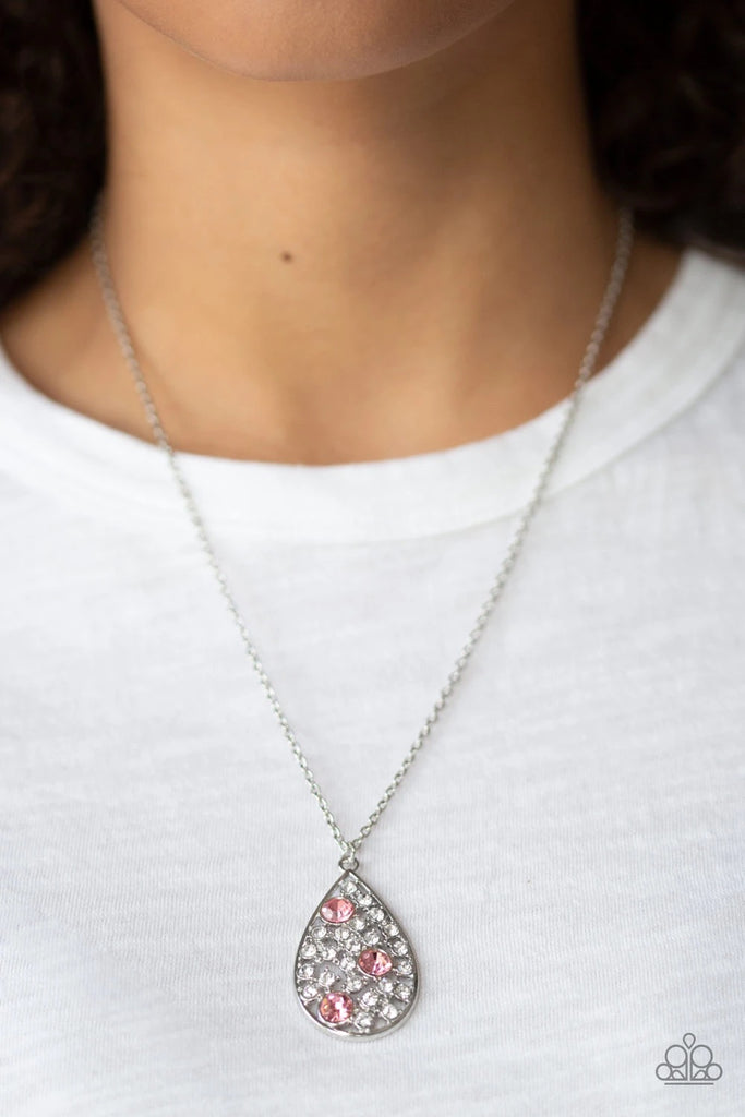 A collection of glassy white and glittery pink rhinestones coalescing inside a shimmery silver teardrop frame, creating a refined pendant. Features an adjustable clasp closure.  Sold as one individual necklace. Includes one pair of matching earrings.