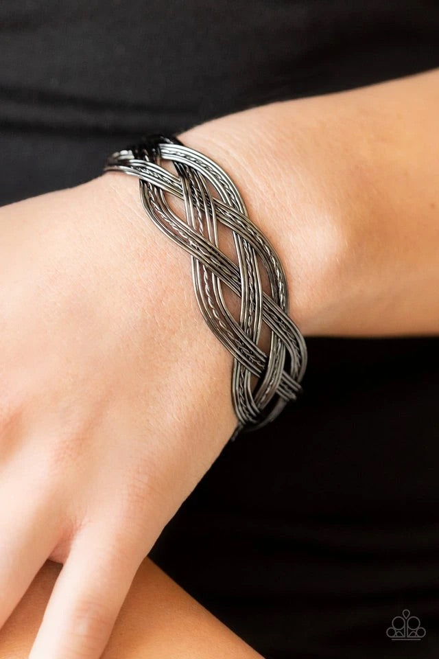 A collection of plain and twisted gunmetal wires decoratively weave across the wrist, resulting into an edgy cuff.  Sold as one individual bracelet.