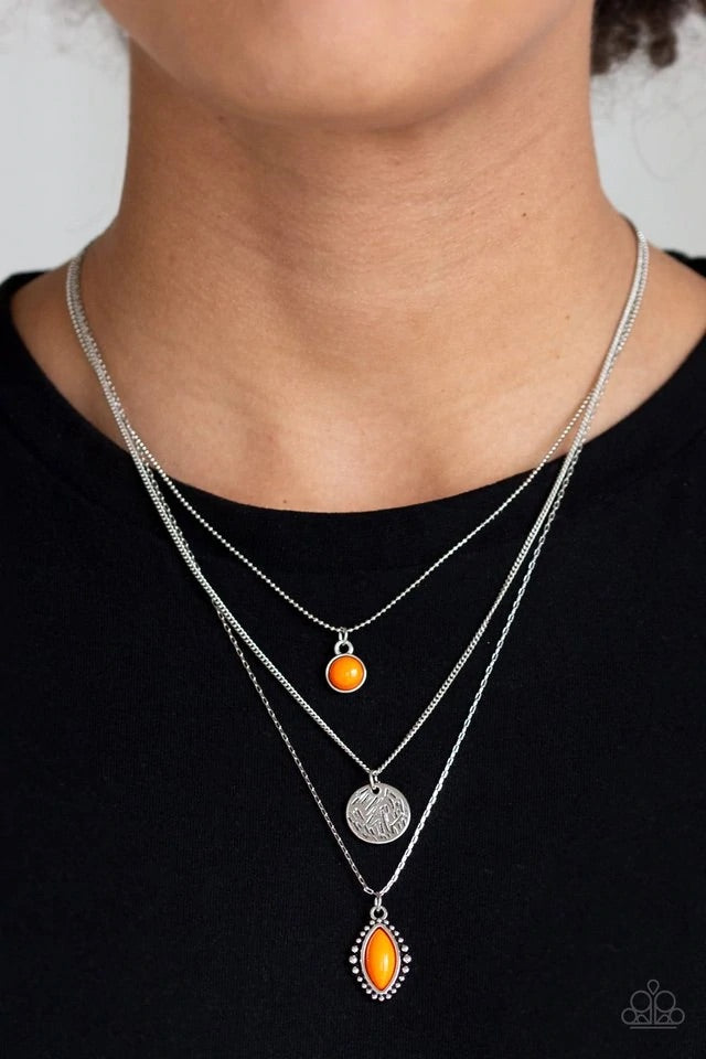 Three mismatched silver chains layer below the collar. A round orange bead swings from the uppermost chain, above a scratched silver disc, and marquise-shaped orange bead for a colorfully layered look. Features an adjustable clasp closure. Sold as one individual necklace. Includes one pair of matching earrings.