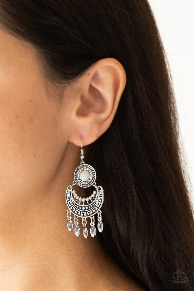 Dotted with a shiny gray beaded center, a round silver frame gives way to an ornate silver crescent. Dainty silver beads swing from the bottom of the stacked frames, adding a whimsical fringe to the tribal inspired lure. Earring attaches to a standard fishhook fitting. Sold as one pair of earrings.