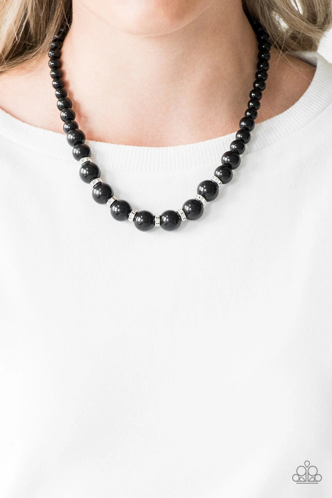 Gradually increasing in size near the bottom, classic black beads drape below the collar. Rhinestone encrusted rings are sprinkled between the dramatic beads, adding sparkling accents to the timeless palette. Features an adjustable clasp closure.  Sold as one individual necklace. Includes one pair of matching earrings.
