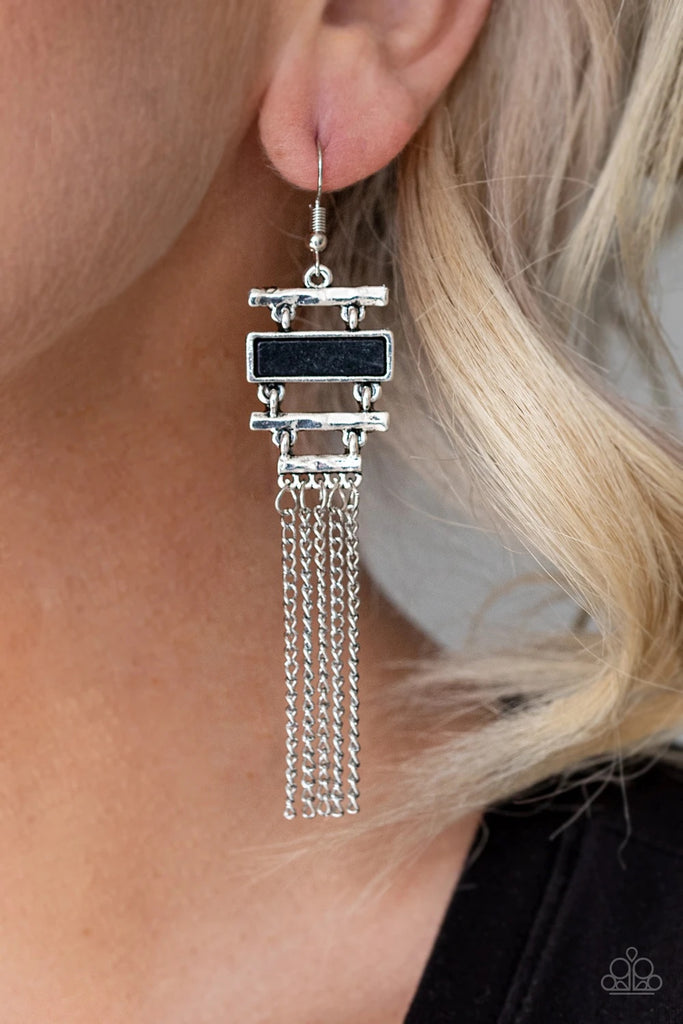 Infused with a flat black stone frame, hammered silver bars stack into an abstract lure. Shimmery silver chains stream from the bottom, creating a whimsical fringe. Earring attaches to a standard fishhook fitting.  Sold as one pair of earrings.  